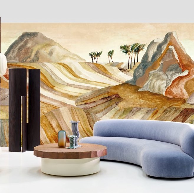 Moderne woonkamer met een afgeronde bank en houten salontafel, tegen een kleurrijk woestijnlandschap op het Arte Kharga Zerzura 74060 panorama behang in warme zandtinten.
