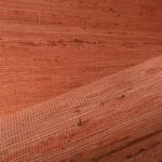 Close-up van Arte behang Kudzu 54536 in een geweven structuur met een warme roestoranje kleur.