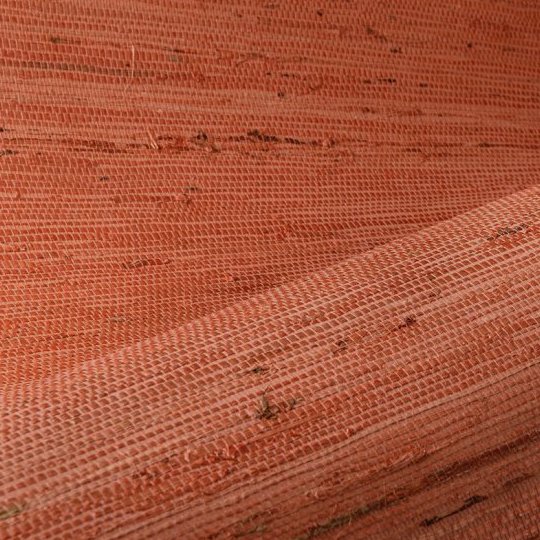 Close-up van Arte behang Kudzu 54536 in een geweven structuur met een warme roestoranje kleur.