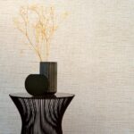 Zwarte metalen bijzettafel met twee moderne vazen en droogbloemen tegen Arte-behang Le Papier Tissé.