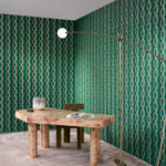 Moderne kamer met groen Arte-behang LeCouturier Franges 58520 en een houten bureau met boek en decoratie.