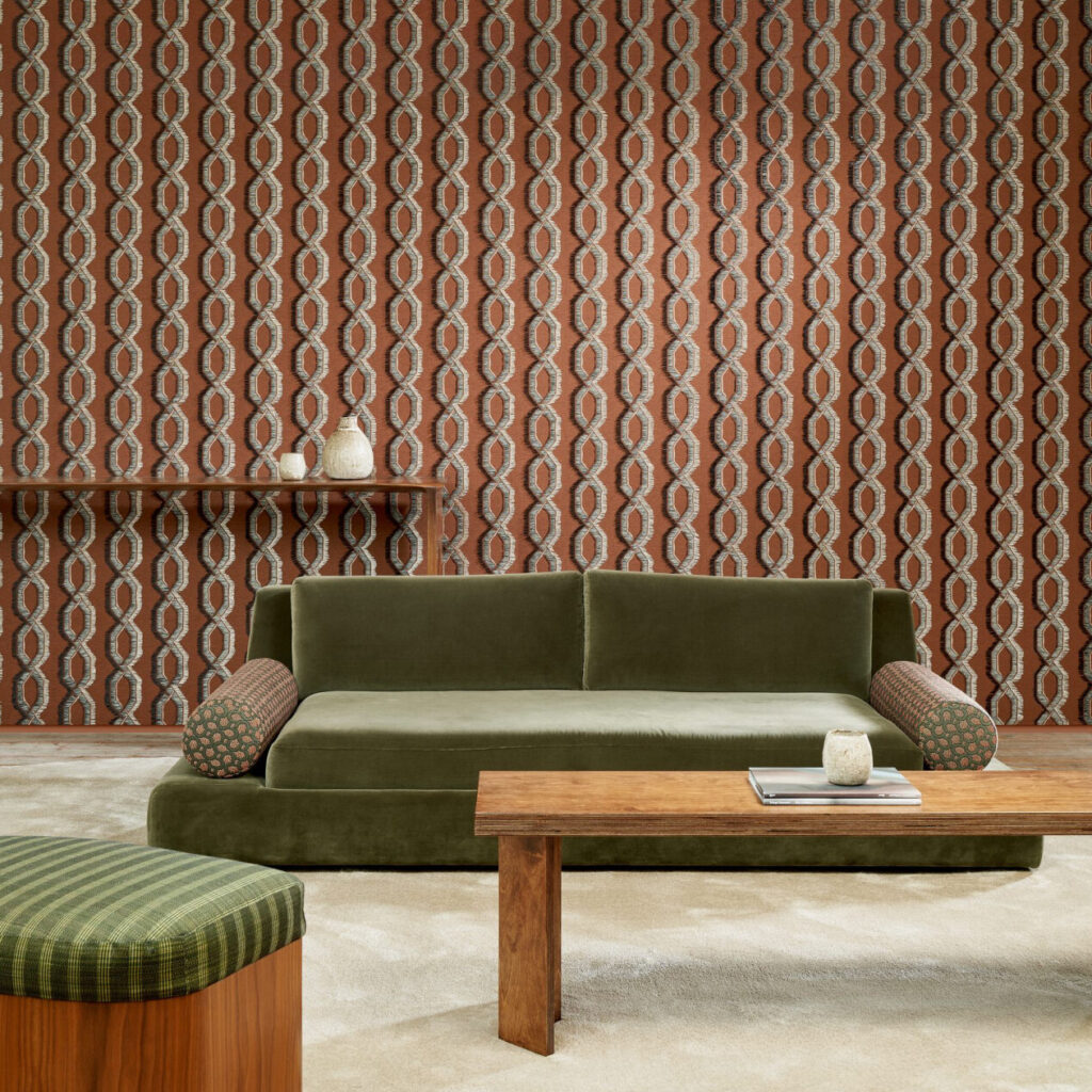 Stijlvolle woonkamer met Arte-behang Le Couturier Franges 58524 in aardetinten, een groene fluwelen bank en houten meubels.