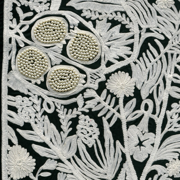 Gedetailleerd wit Arte-behang La Perle van Le Couturier met geborduurde bloemen en granaatappels op een donkere achtergrond.