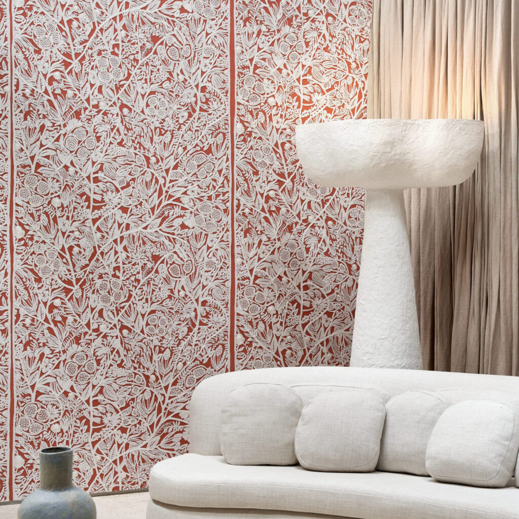 Sfeervolle woonruimte met Arte La Perle behang van Le Couturier in rood-wit bloemenmotief, een licht sculpturaal vloerlamp en een crèmekleurige bank.