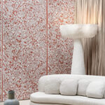 Sfeervolle woonruimte met Arte La Perle behang van Le Couturier in rood-wit bloemenmotief, een licht sculpturaal vloerlamp en een crèmekleurige bank.