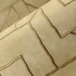 Detail van Arte behang Le Couturier La Dérive 58501 met een verfijnd patroon in reliëf op een zandkleurige achtergrond.