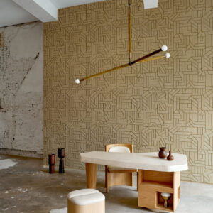 Sfeervol interieur met Arte behang La Dérive 58501, een geometrisch patroon op een beige muur achter een modern houten bureau en designmeubilair.