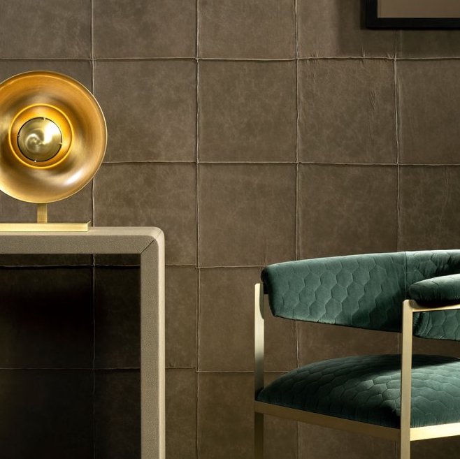 Close-up van een interieur met Arte-behang Les Cuirs, een gouden tafellamp en een groene fluwelen stoel met honingraatpatroon.