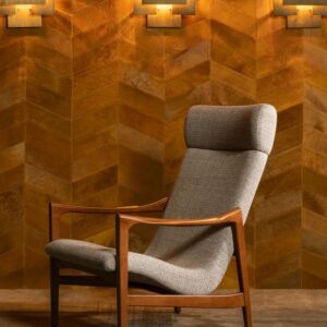 Grijze designfauteuil voor een wand met Arte-behang uit de Les Cuirs-collectie in warme bruintinten.