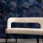 Luxe Arte-behang uit de Les Cuirs-collectie met donkerblauw visgraatpatroon achter een moderne beige bank.