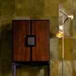Donkergroene leren Arte-behangwand met een houten kast en een goudkleurige designlamp.