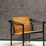 Designstoel met lederen zitting en rugleuning voor een wand met Arte-behang Lino Aspero.