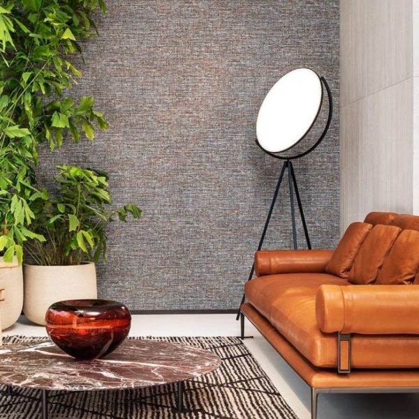 Stijlvolle woonkamer met Arte-behang Lino Aspero, een leren bank, een ronde marmeren salontafel en grote planten.
