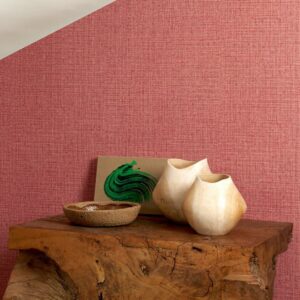 Sfeervolle setting met rood Arte Nongo behang uit de Gitane collectie, houten decorvazen en een kunstwerkje op een robuuste houten tafel.