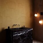 Luxe badkamer met Arte-behang Oblong, een zwart marmeren wastafel en sfeervolle hanglampen.