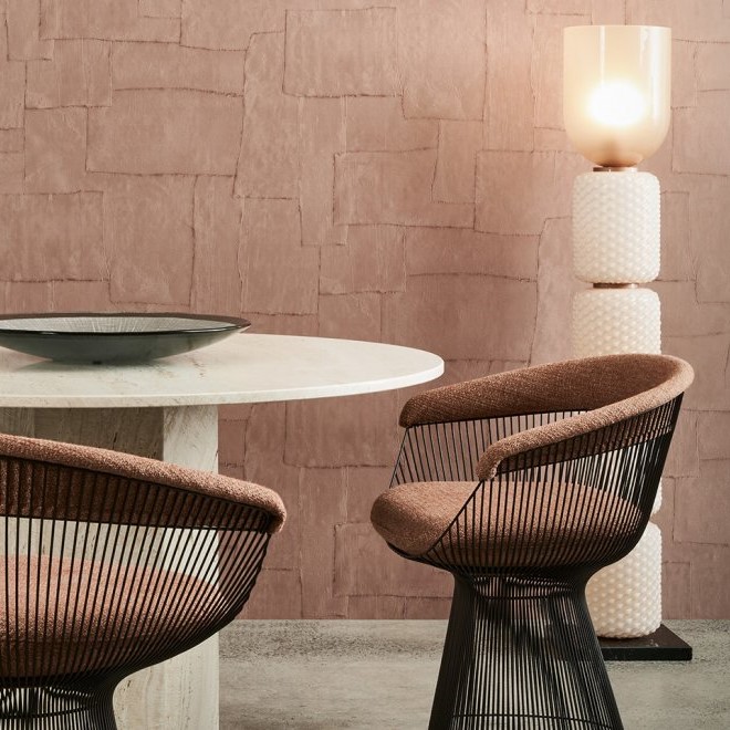 Moderne interieursetting met Arte Oblong behang, een ronde stenen tafel, twee designstoelen en een opvallende vloerlamp.