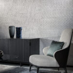 Moderne woonkamer met Arte behang Papyrus 48550, een design fauteuil en een zwarte kast met decoratieve vazen.