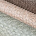 Drie rollen Arte behang uit de Puro 27000 collectie met een geweven textuur in aardetinten.