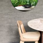 Moderne interieurhoek met Arte Textura Canvas behang, ronde marmeren tafel en houten stoel met rotan zitting.