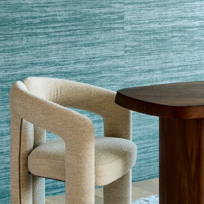 Beige designstoel en houten tafel voor een muur met blauw Arte-behang Textura Tasar 72032A.