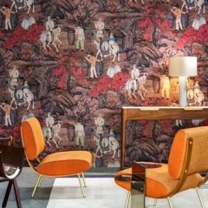 Interieur met oranje stoelen en houten tafel tegen een wand met Arte-behang uit de Toile de Tibet Decors en Panoramiques collectie, met oosterse taferelen en rode bomen.
