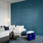 Moderne woonkamer met blauw Arte Wild Silk Ghicha behang en een witte loungebank met blauwe accenten.