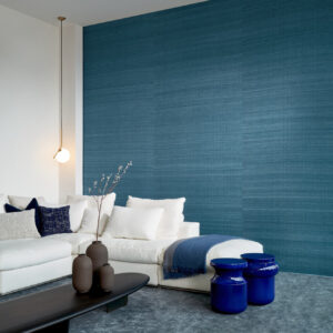 Moderne woonkamer met blauw Arte Wild Silk Ghicha behang en een witte loungebank met blauwe accenten.