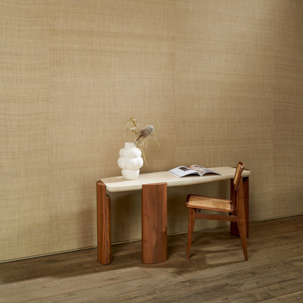 Interieur met Arte-behang WildSilk GhichaSilk, een houten tafel met vaas en boek, en een houten stoel op een houten vloer.