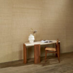 Interieur met Arte-behang WildSilk GhichaSilk, een houten tafel met vaas en boek, en een houten stoel op een houten vloer.