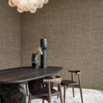 Modern interieur met Arte Wild Silk Katia Silk 86500 behang, een organisch gevormde donkere houten tafel, designstoelen en decoratieve vazen.