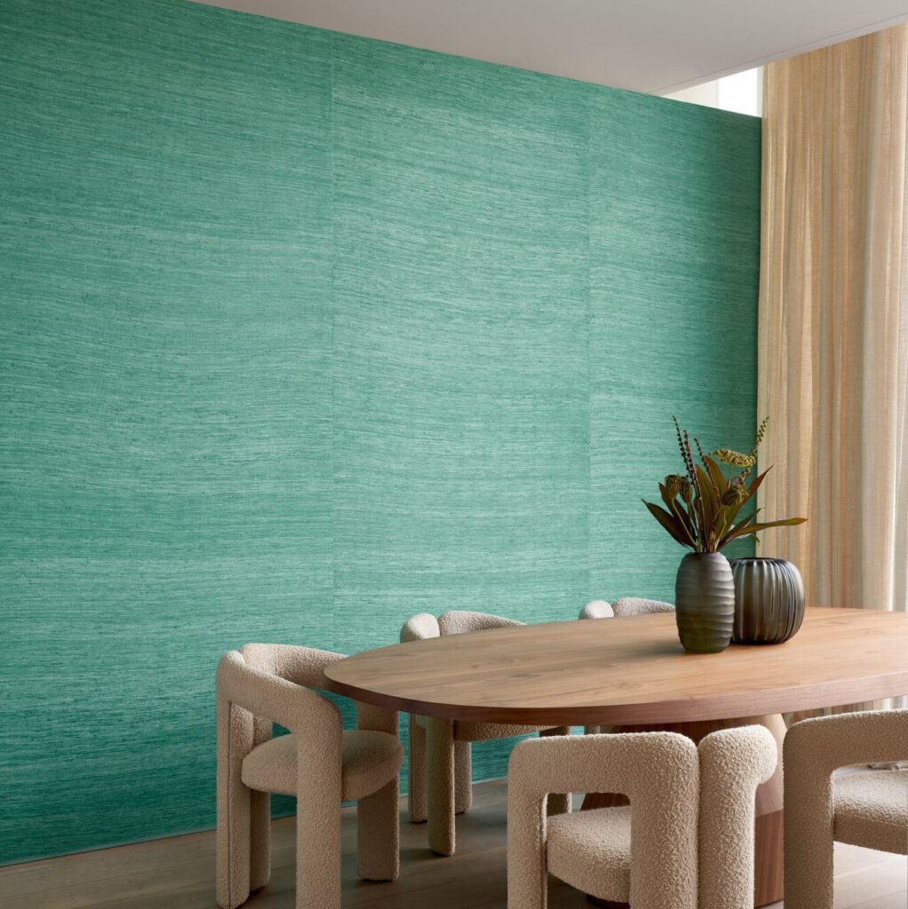 Moderne eethoek met een houten tafel, crèmekleurige designstoelen en groene Arte WildSilk PureSilk 86535-behang op de muur.