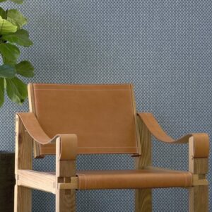 Lederen designstoel met houten frame voor een Arte Wildwalk Ferox1-behang met subtiel patroon.