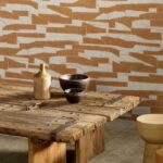 Rustieke houten tafel met aardewerken decoratie voor een muur met geel Arte Costura Gabarit 57564 behang in abstract patroon.