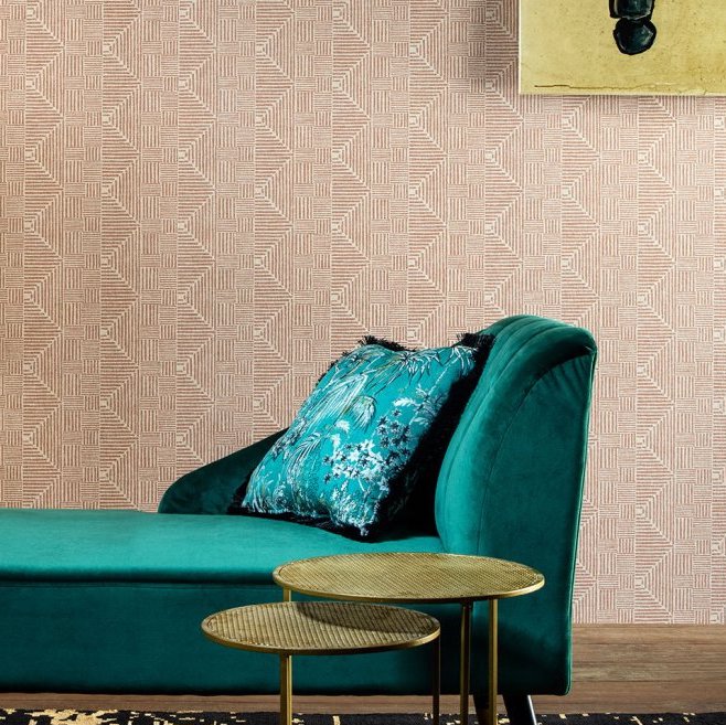 Groen fluwelen chaise longue met sierkussen voor een wand met Arte Essentials Macrame behang in geometrisch patroon.