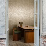 Modern interieur met houten meubilair en Arte Impasto 60101-behang met een goudkleurig, grof textuurpatroon.