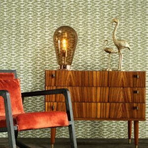 Retro interieuropstelling met Behang Essentials Travellers Calanco, houten dressoir, fluwelen stoel en decoratieve accessoires.