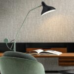 Moderne werkplek met Arte Les Tricots Boucle behang, een designlamp, mintgroene stoel en open tijdschrift op een houten bureau.