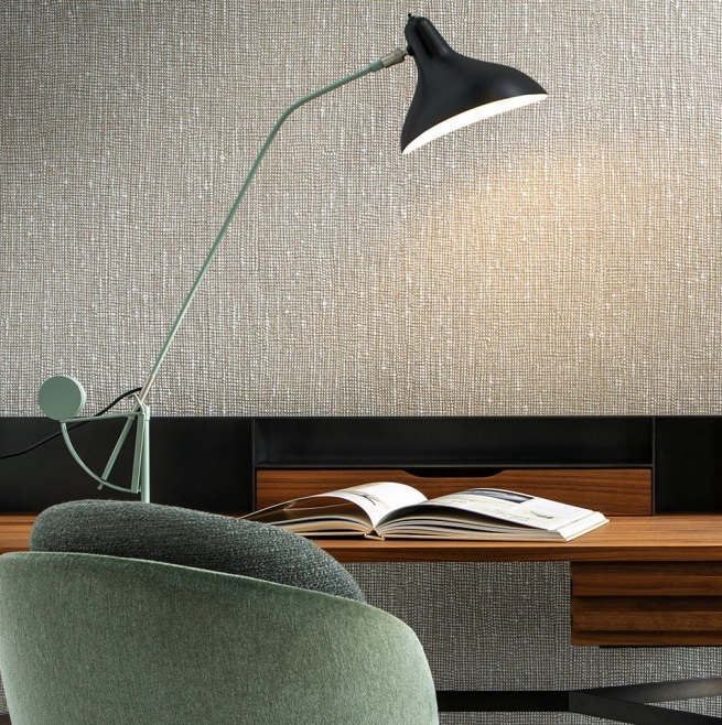 Moderne werkplek met Arte Les Tricots Boucle behang, een designlamp, mintgroene stoel en open tijdschrift op een houten bureau.