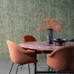 Interieur met Arte Les Tricots Cashmere behang, roze marmeren tafel en roestbruine stoffen stoelen.
