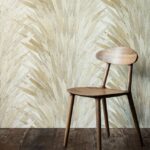 Houten stoel voor muur met naturel Abanico-behang van Arte in bladdessin.