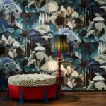 Rijke interieursetting met Arte-behang 'Allombra dei cipressi', een rode ottoman en een klassieke rode lamp met blauwgroene kap.