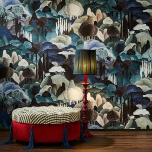Rijke interieursetting met Arte-behang 'Allombra dei cipressi', een rode ottoman en een klassieke rode lamp met blauwgroene kap.
