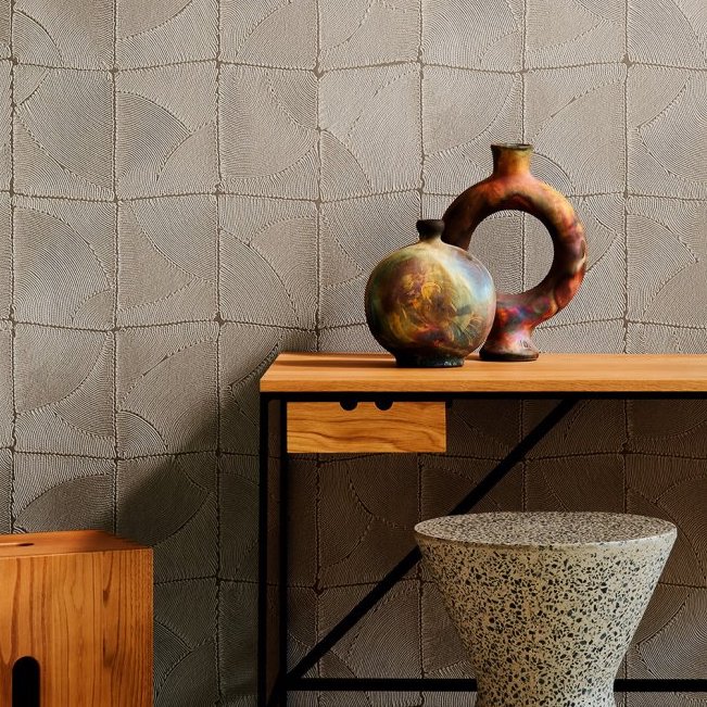 Moderne interieursetting met Arte Atlas 64534 behang, een houten tafel met kunstzinnige vazen en een terrazzo kruk.