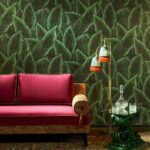 Rode fluwelen bank tegen Arte-behang Bird of Paradise met groen tropisch bladerpatroon.