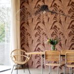 Moderne eetkamer met Arte behang Botanic 64502 in warme tinten en natuurlijke rotanmeubels.
