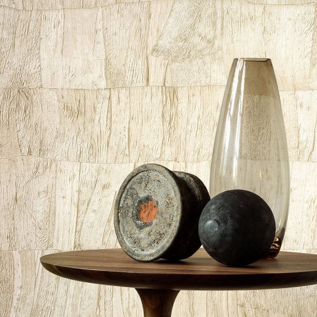 Stijlvolle opstelling met Arte behang Capas 34306 op de achtergrond, en decoratieve objecten op een houten tafel.