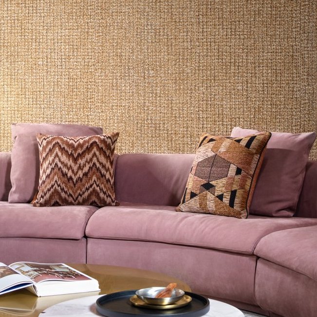 Roze fluwelen bank met sierkussens voor een muur met Arte Cashmere 73061 behang in een warme textuur.