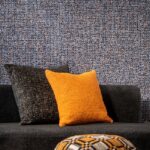 Gezellige zithoek met Arte Cashmere 73063 behang en sierkussens in zwart en oranje.
