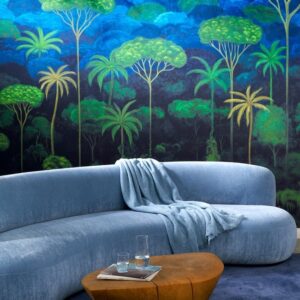 Blauw fluwelen bank voor een muur met tropisch Arte-behang Ciel Tropical in groene en blauwe tinten.