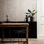 Moderne keuken met Arte Emaille behang, zwart meubilair en houten eettafel met draadstoelen.
